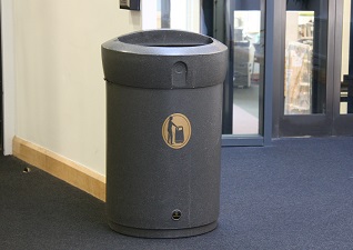Envoy™ Indoor Litter Bin in grey with D-shaped open top, situated by building entrance doors