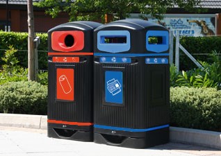 Glasdon Jubilee™ Outdoor Recycling Bins for newspapers and cans, in front of grassy area