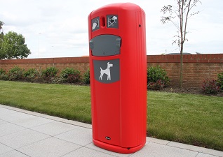 Retriever City™ Dog Waste Bin with sack dispenser in red with grey detailing and sited on paving slabs