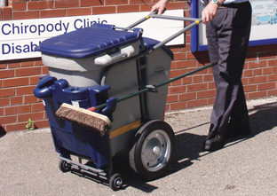 Single Space-Liner™ Street Orderly Barrow in grey and dark blue next to Chiropody Clinic
